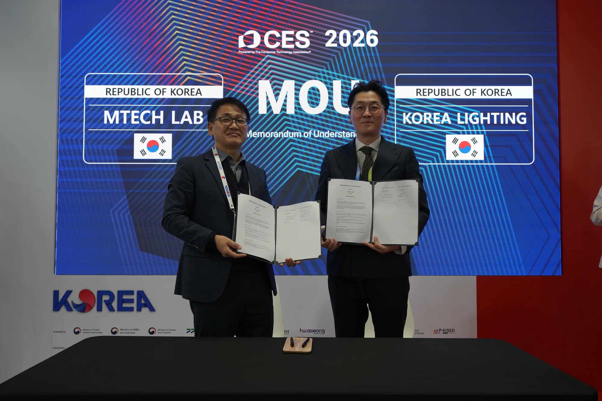 MTechLab and Korea Lighting representatives holding their signed CES 2026 memorandum of understanding